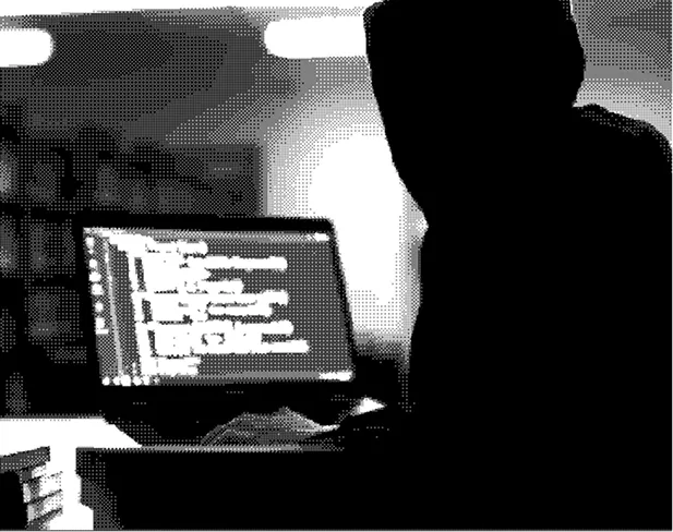 Silhouette of a person sitting at a desk working on a laptop displaying lines of code in a dimly lit room.
