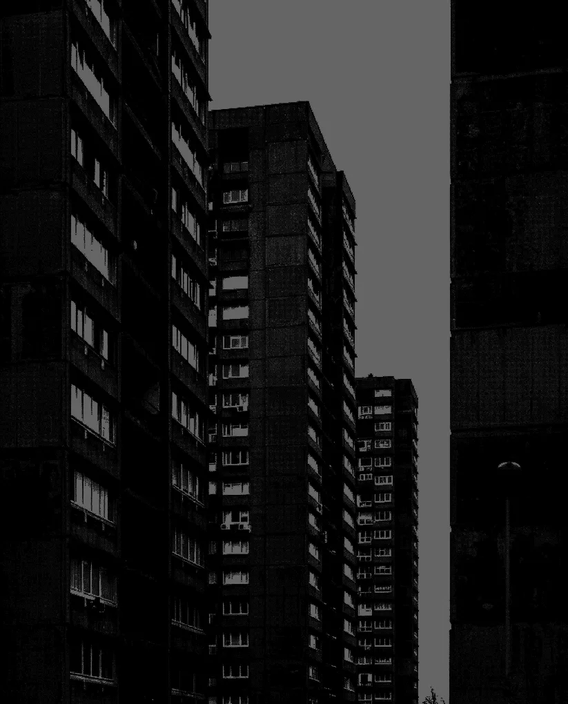Tall residential apartment buildings with many windows under a clear sky, viewed from street level.